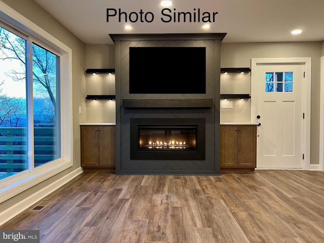 unfurnished living room with a large fireplace and wood-type flooring