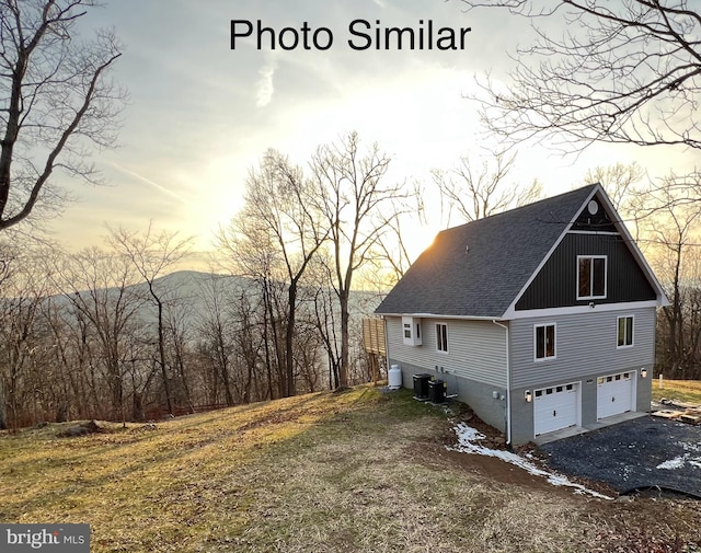 property exterior at dusk with cooling unit and a garage