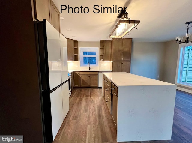 kitchen featuring sink, hanging light fixtures, hardwood / wood-style flooring, dishwashing machine, and a kitchen island