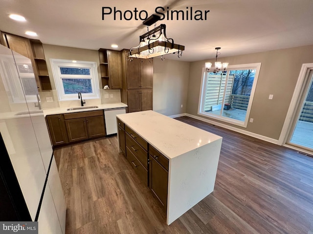 kitchen with pendant lighting, dishwasher, sink, a kitchen island, and dark hardwood / wood-style flooring