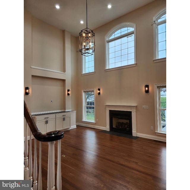 interior space featuring dark hardwood / wood-style flooring, a wealth of natural light, and a towering ceiling