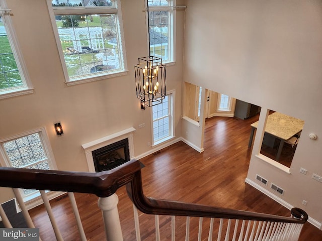 entryway with dark hardwood / wood-style floors, a healthy amount of sunlight, a notable chandelier, and a high ceiling