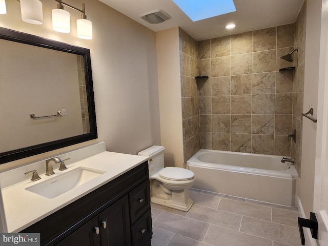 full bathroom with vanity, a skylight, tiled shower / bath combo, toilet, and tile patterned flooring