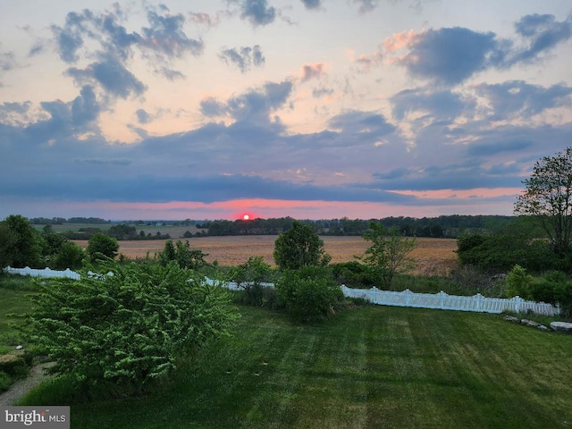 yard at dusk featuring a rural view