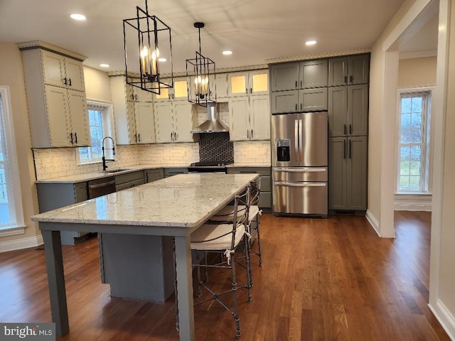 kitchen with a breakfast bar area, a center island, dark hardwood / wood-style floors, wall chimney exhaust hood, and stainless steel refrigerator with ice dispenser