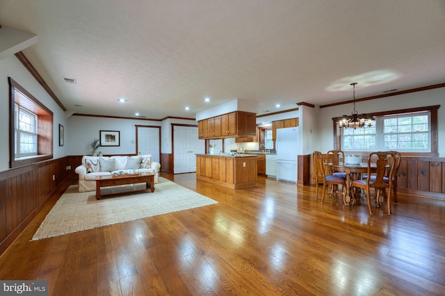 living room featuring a textured ceiling, light hardwood / wood-style flooring, crown molding, and a chandelier