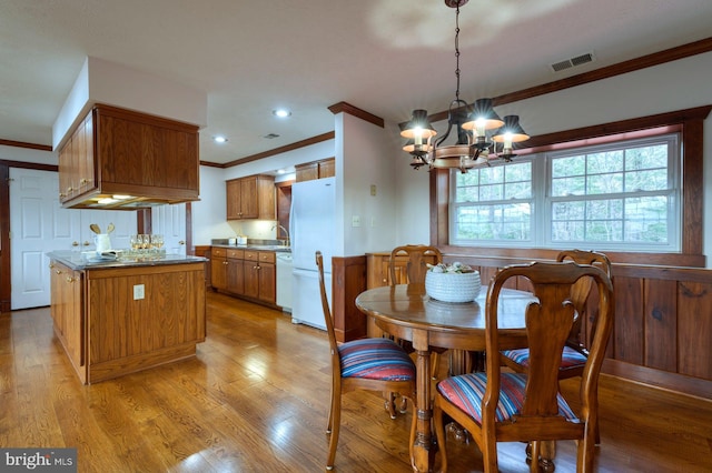 dining space featuring a notable chandelier, light wood-type flooring, and ornamental molding