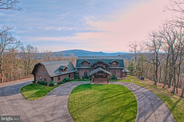 log cabin with a mountain view and a lawn