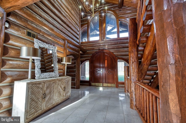 tiled foyer entrance featuring rustic walls and a towering ceiling