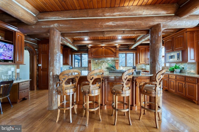 kitchen featuring beamed ceiling, stainless steel microwave, and wooden ceiling