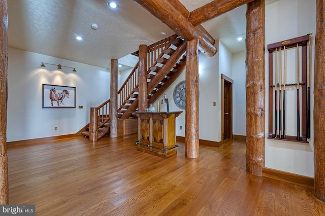 interior space with hardwood / wood-style flooring, a towering ceiling, and a textured ceiling