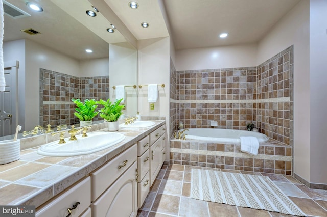 bathroom featuring tiled tub and vanity