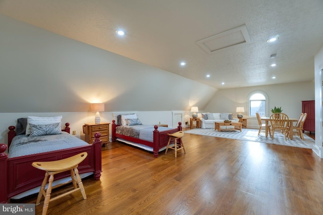 bedroom featuring wood-type flooring, a textured ceiling, and vaulted ceiling