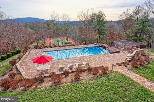 view of swimming pool featuring a mountain view, a patio, and a lawn