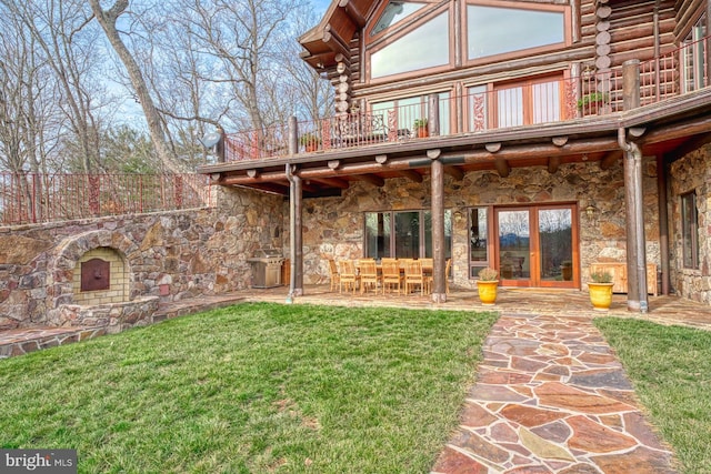 rear view of house with a lawn, a balcony, and a patio