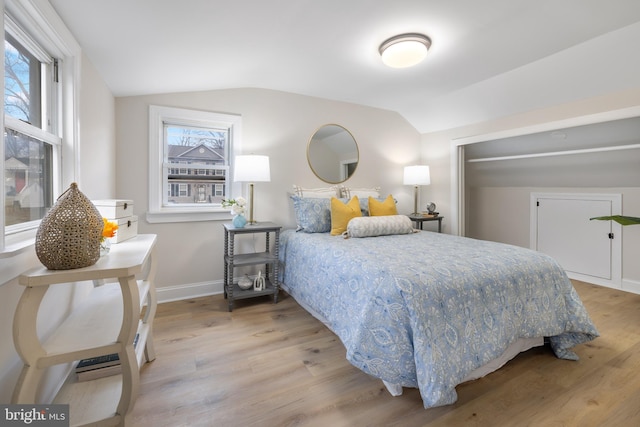 bedroom featuring wood-type flooring, lofted ceiling, and multiple windows