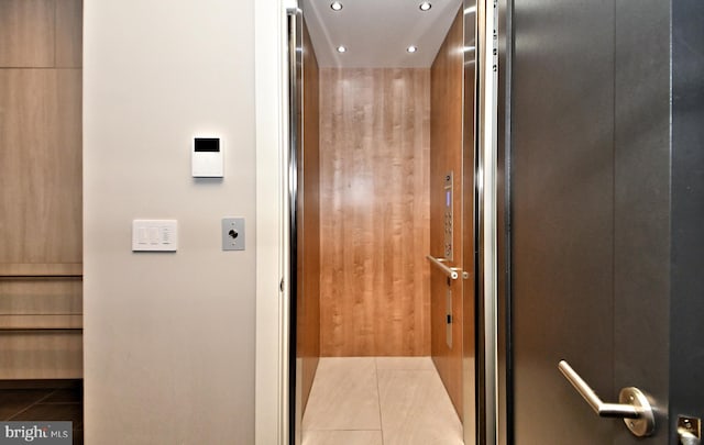 hall with wood walls and light tile patterned floors