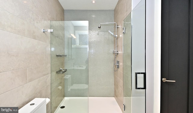 bathroom with tile walls, an enclosed shower, and toilet