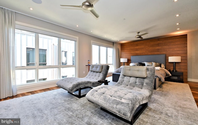 bedroom featuring multiple windows, wood walls, and wood-type flooring