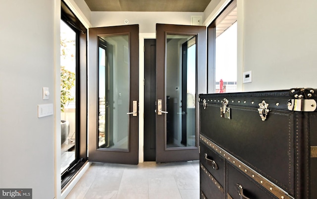 doorway to outside with lofted ceiling, a healthy amount of sunlight, and light tile patterned flooring