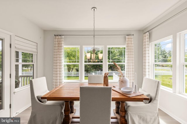 dining area with baseboards, plenty of natural light, an inviting chandelier, and wood finished floors