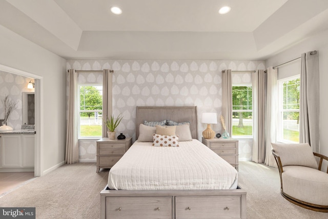 bedroom with wallpapered walls, a tray ceiling, recessed lighting, and light colored carpet