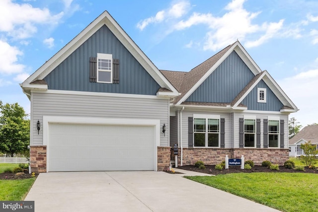 craftsman house with stone siding, board and batten siding, concrete driveway, and a front yard