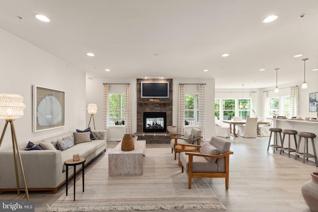 living room with recessed lighting, light wood-type flooring, and a multi sided fireplace