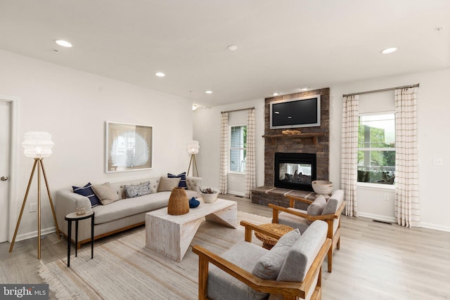 living area with light wood-style flooring, recessed lighting, a multi sided fireplace, and baseboards