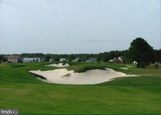 view of property's community featuring view of golf course and a yard