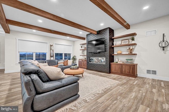 living room featuring beamed ceiling, light wood-type flooring, and a fireplace