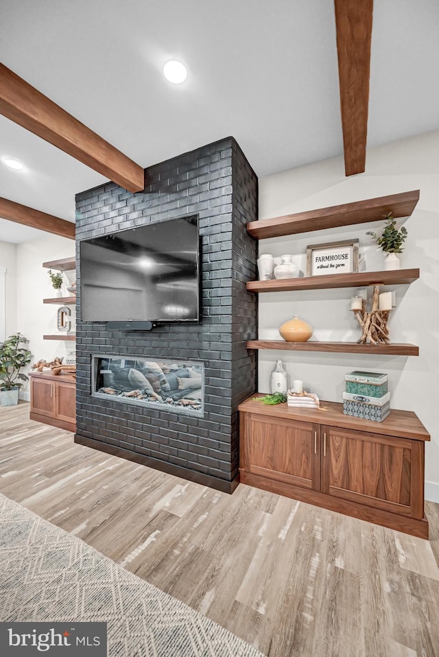 living room with a fireplace, light hardwood / wood-style flooring, and beamed ceiling