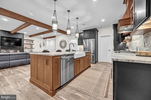 kitchen featuring sink, stainless steel appliances, decorative light fixtures, decorative backsplash, and a center island with sink