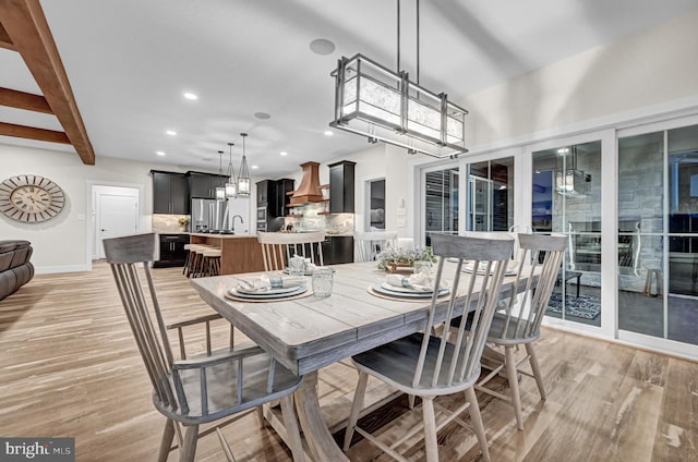 dining room featuring beamed ceiling and light hardwood / wood-style floors