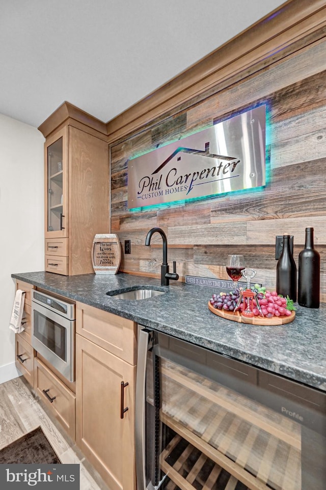 kitchen featuring sink, dark stone countertops, wood walls, oven, and light hardwood / wood-style floors