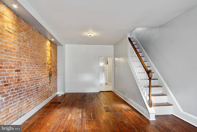 interior space with hardwood / wood-style flooring and brick wall