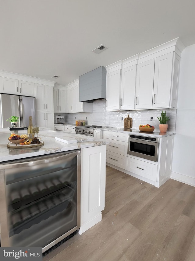 kitchen with tasteful backsplash, white cabinetry, premium range hood, and high end refrigerator