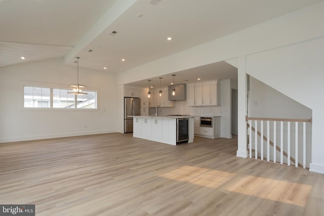 unfurnished living room featuring lofted ceiling with beams, light hardwood / wood-style flooring, wine cooler, and sink