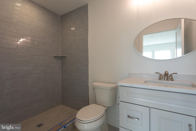 bathroom featuring vanity, toilet, and a tile shower