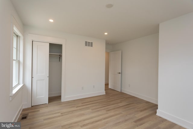 unfurnished bedroom with light hardwood / wood-style flooring and a closet