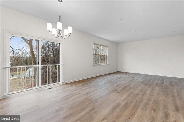 empty room with light hardwood / wood-style flooring and a chandelier