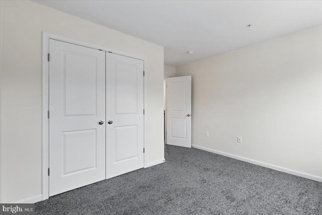 unfurnished bedroom featuring dark colored carpet and a closet