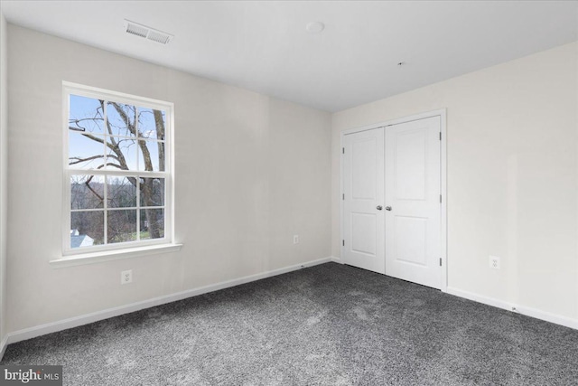 unfurnished bedroom with dark carpet and a closet