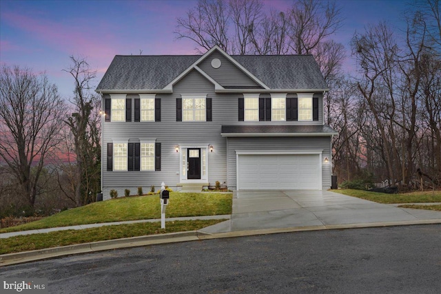 colonial inspired home with a lawn and a garage