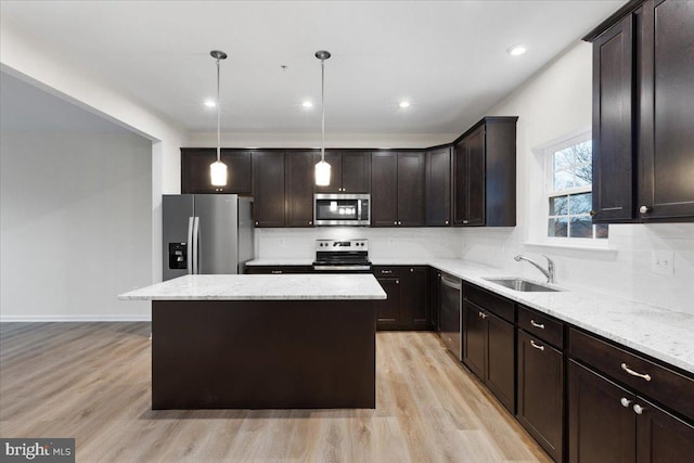 kitchen featuring hanging light fixtures, sink, light hardwood / wood-style flooring, appliances with stainless steel finishes, and a kitchen island