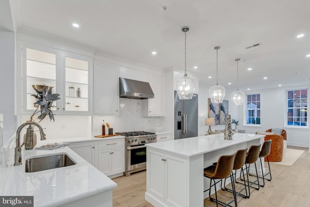 kitchen with white cabinetry, sink, extractor fan, a kitchen island, and high end appliances