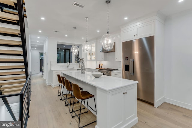 kitchen with white cabinetry, sink, pendant lighting, a kitchen island, and appliances with stainless steel finishes