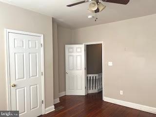 unfurnished bedroom with ceiling fan and dark wood-type flooring