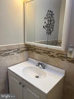 bathroom featuring vanity and tile walls