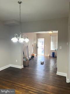 unfurnished dining area featuring dark hardwood / wood-style floors and an inviting chandelier